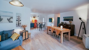 Una sala moderna con un sofá, una mesa de comedor de madera y una cocina al fondo.