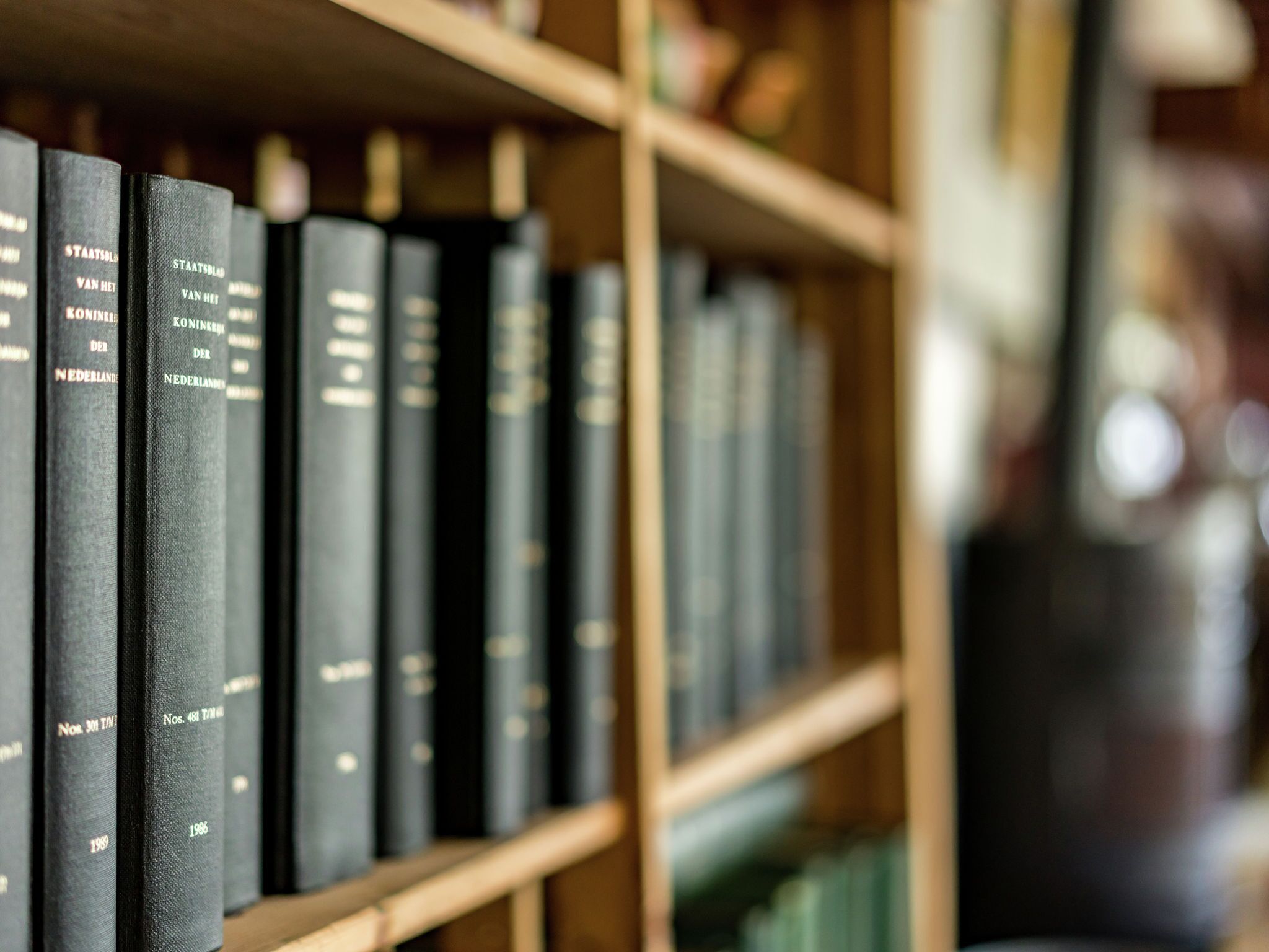 A row of black books on a wooden bookshelf.