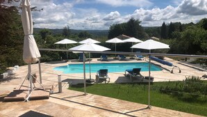 A swimming pool with lounge chairs and umbrellas, surrounded by greenery and a clear sky. - Holiday Home Provence With Pool (Cereste)