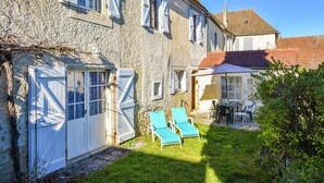 A stone building with a white door, a small window, and a balcony with two chairs. - Vintage Retreat in Montfaucon (Montfaucon)