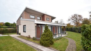 Ein modernes, zweistöckiges Haus mit Wintergarten, Ziegelaußenwand und gepflegtem Rasen.