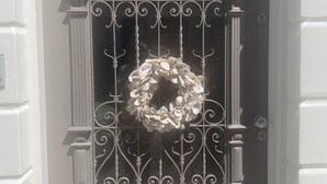 Un edificio bianco con un balcone caratterizzato da una ringhiera in ferro battuto e una ghirlanda.