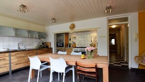 Una cucina moderna con un tavolo da pranzo in legno, sedie bianche e un'isola centrale con un vaso di fiori.