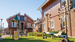 Een speelplaats met een glijbaan en klimconstructies, omringd door een gazon en een blauw pad.