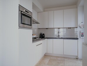 A modern kitchen with white cabinets, a stainless steel oven, and a gas stove. - Luxury Apartment Near the North Sea (Egmond aan Zee)