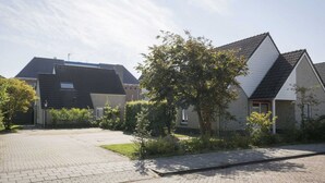 A residential area with houses, paved driveway, and greenery. - Spacious Bungalow in the Cosy Village (De Cocksdorp)