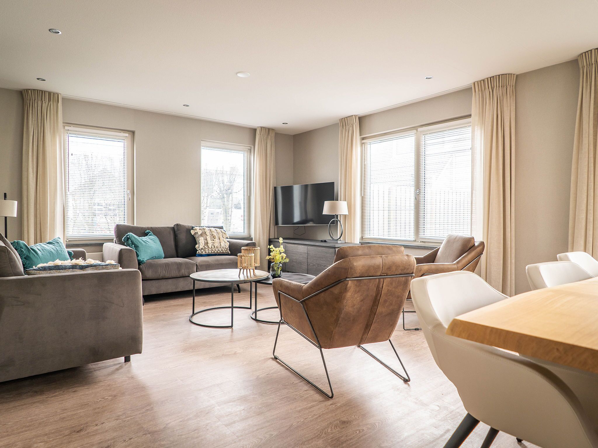 A modern living room with a sofa, armchairs, a coffee table, and a TV.