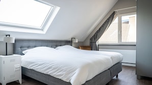 A modern bedroom with a skylight, a bed, bedside tables, and a view of the outside. - Spacious Bungalow in the Cosy Village (De Cocksdorp)