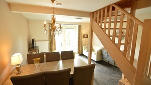 A dining area with a wooden table and chairs, a chandelier, a lamp, and a staircase with a wooden railing.