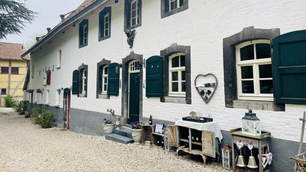 A white building with green shutters and a heart-shaped decoration on the wall.