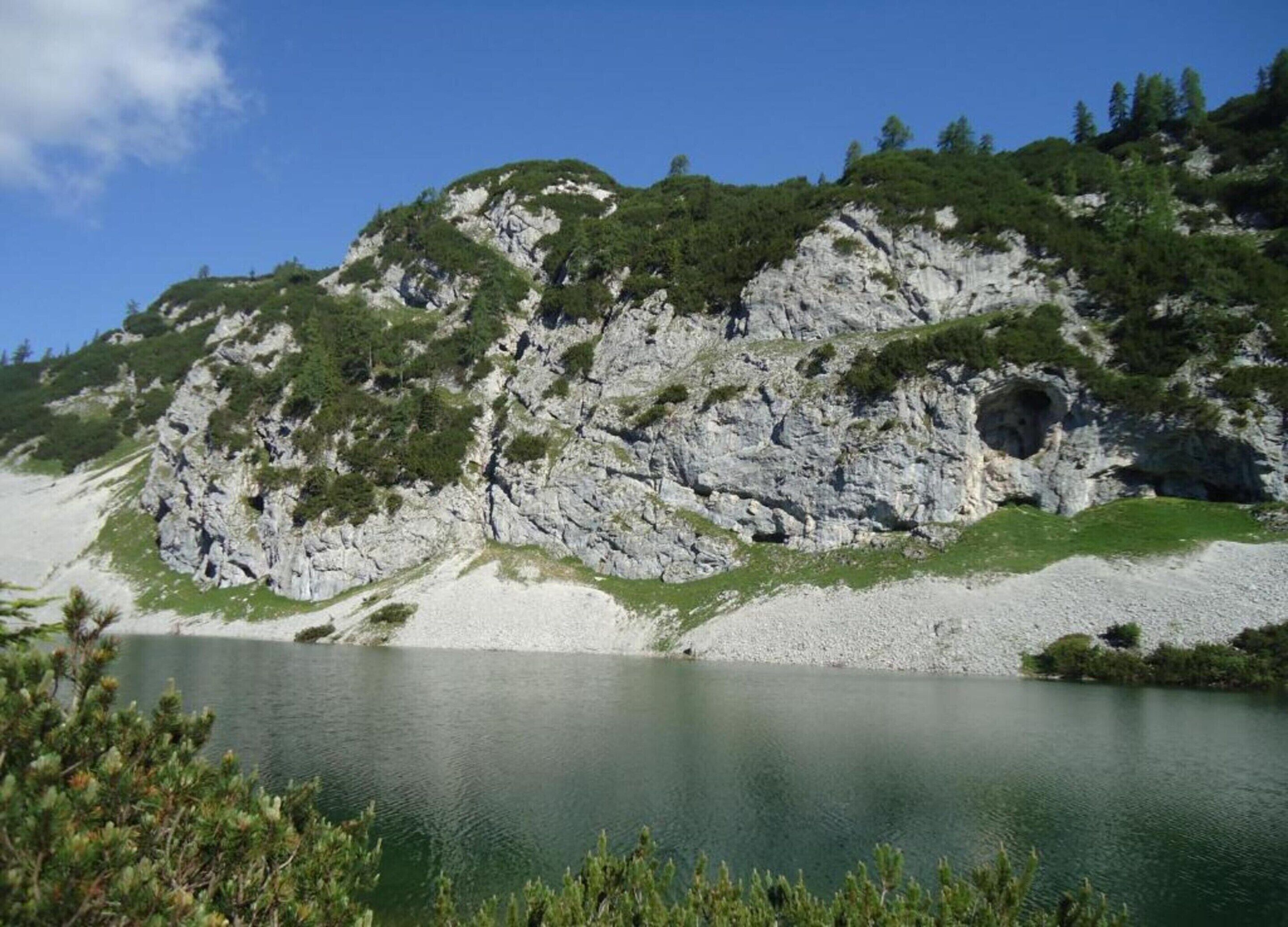 Eine Berglandschaft mit einem See, felsigen Klippen und spärlicher Vegetation.