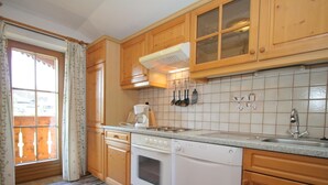 A kitchen with wooden cabinets, a stove, a dishwasher, and a window with curtains. - Cozy Apartment in Embach Austria near Ski Area (Lend)