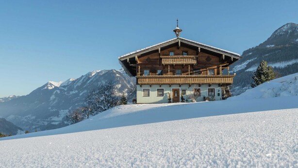 A wooden chalet with a balcony, set against a snowy mountain backdrop. - Cozy Apartment in Embach Austria near Ski Area (Lend)