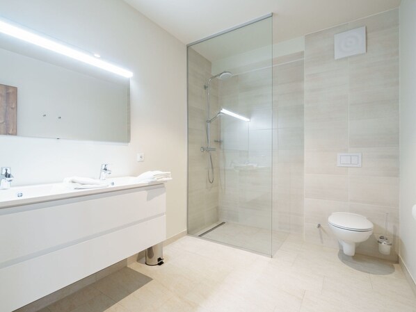 A modern bathroom with a glass-enclosed shower, a white sink, and a toilet.