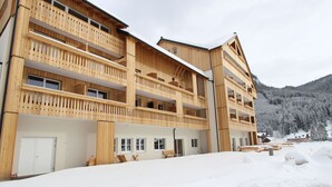 A wooden multi-story building with balconies, a flat roof, and a snowy landscape in the background. - Luxurious Apartment in Gosau Near Ski Area (Gosau)