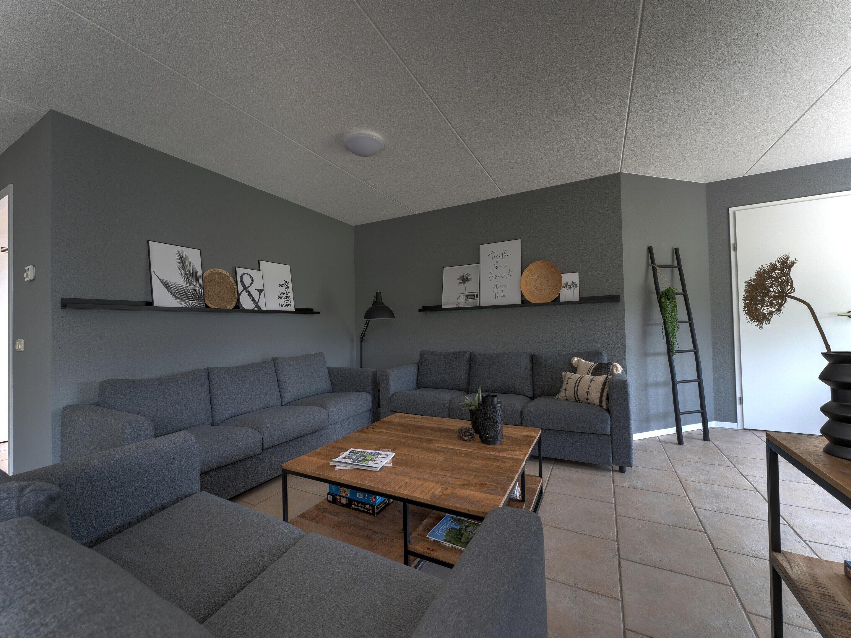 A modern living room with grey sofas, a wooden coffee table, and decorative wall art.
