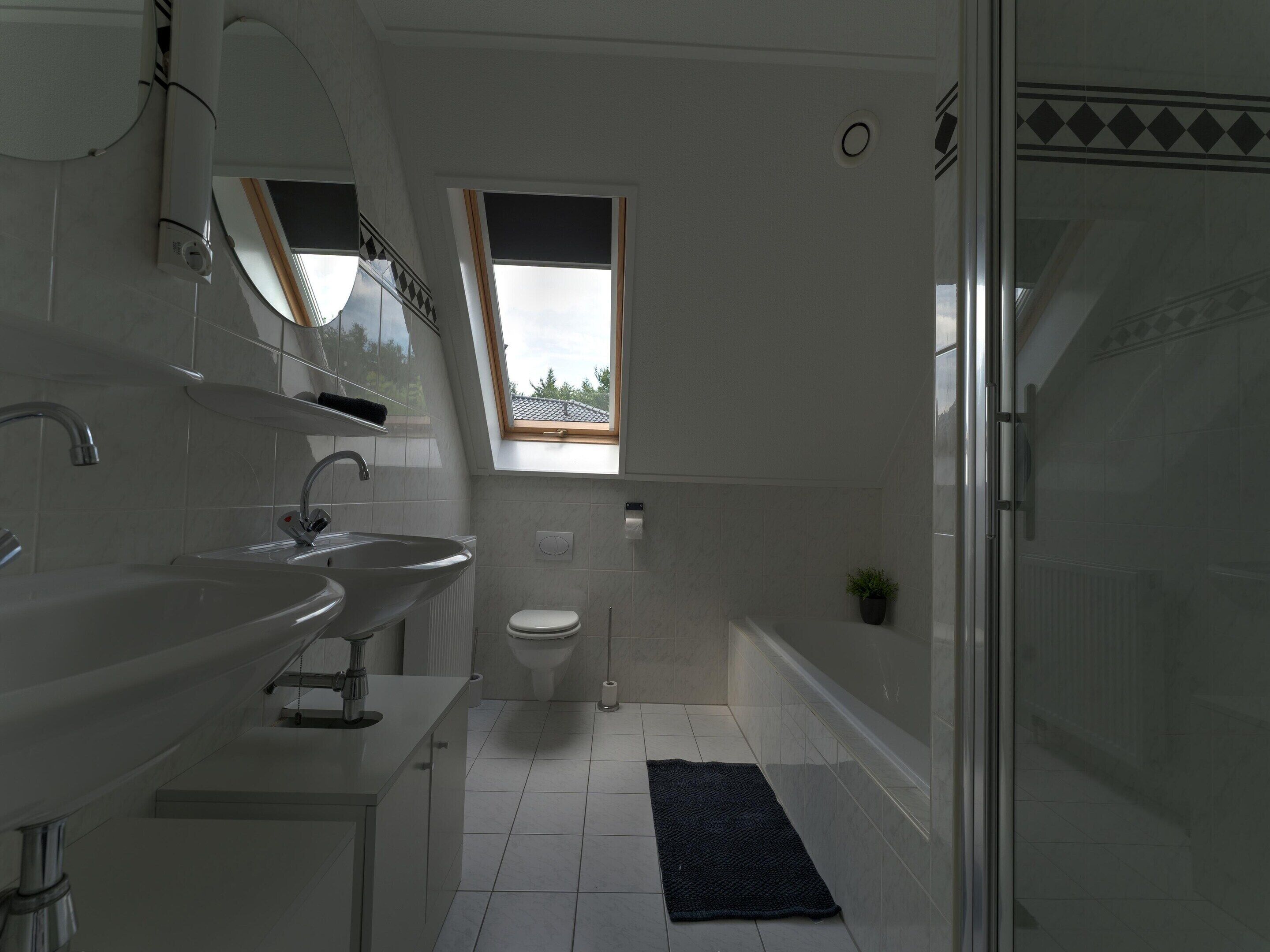 A modern bathroom with a skylight, a shower, and a sink.