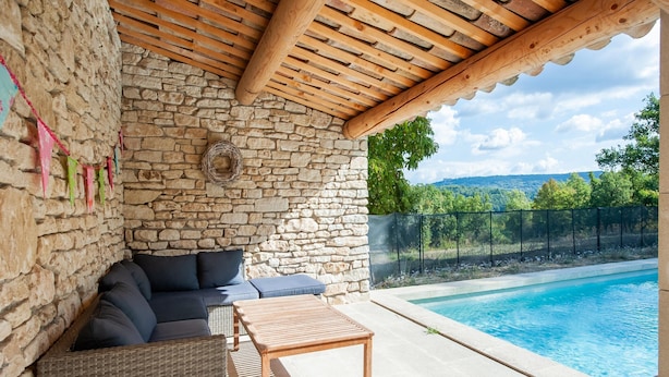 A stone-walled room with a wooden ceiling, a pool, and a view of a vineyard. - Villa in Saignon With Pool and Scenic Views (Saignon)