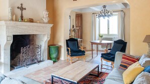A living room with a fireplace, two armchairs, a sofa, a coffee table, and a chandelier. - Villa in Saignon With Pool and Scenic Views (Saignon)