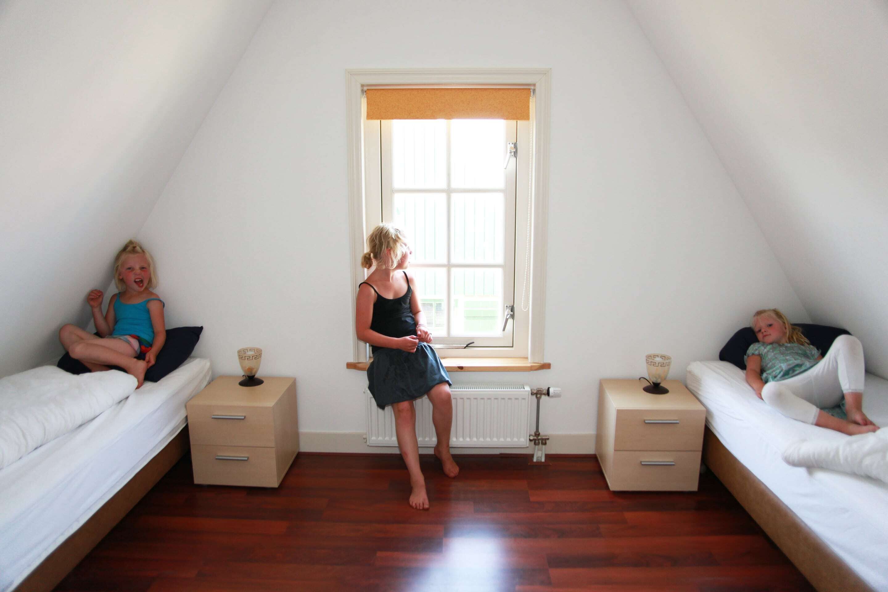 A room with two beds, a window, and a radiator.