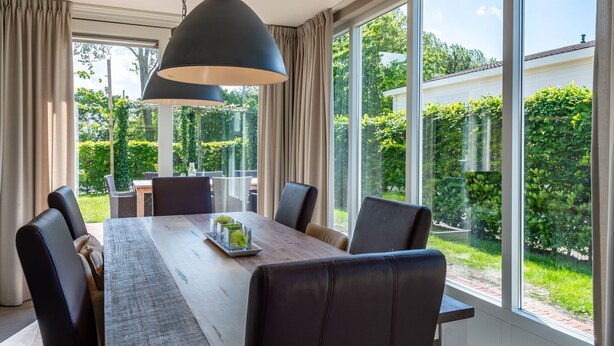 A dining area with a large table, four chairs, and a hanging light fixture. - Detached House Zeeland Near Beach (Kamperland)