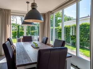 A dining area with a large table, four chairs, and a hanging light fixture. - Detached House Zeeland Near Beach (Kamperland)