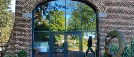 A brick building with a large arched entrance, a glass door, and a sculpture of a swan.