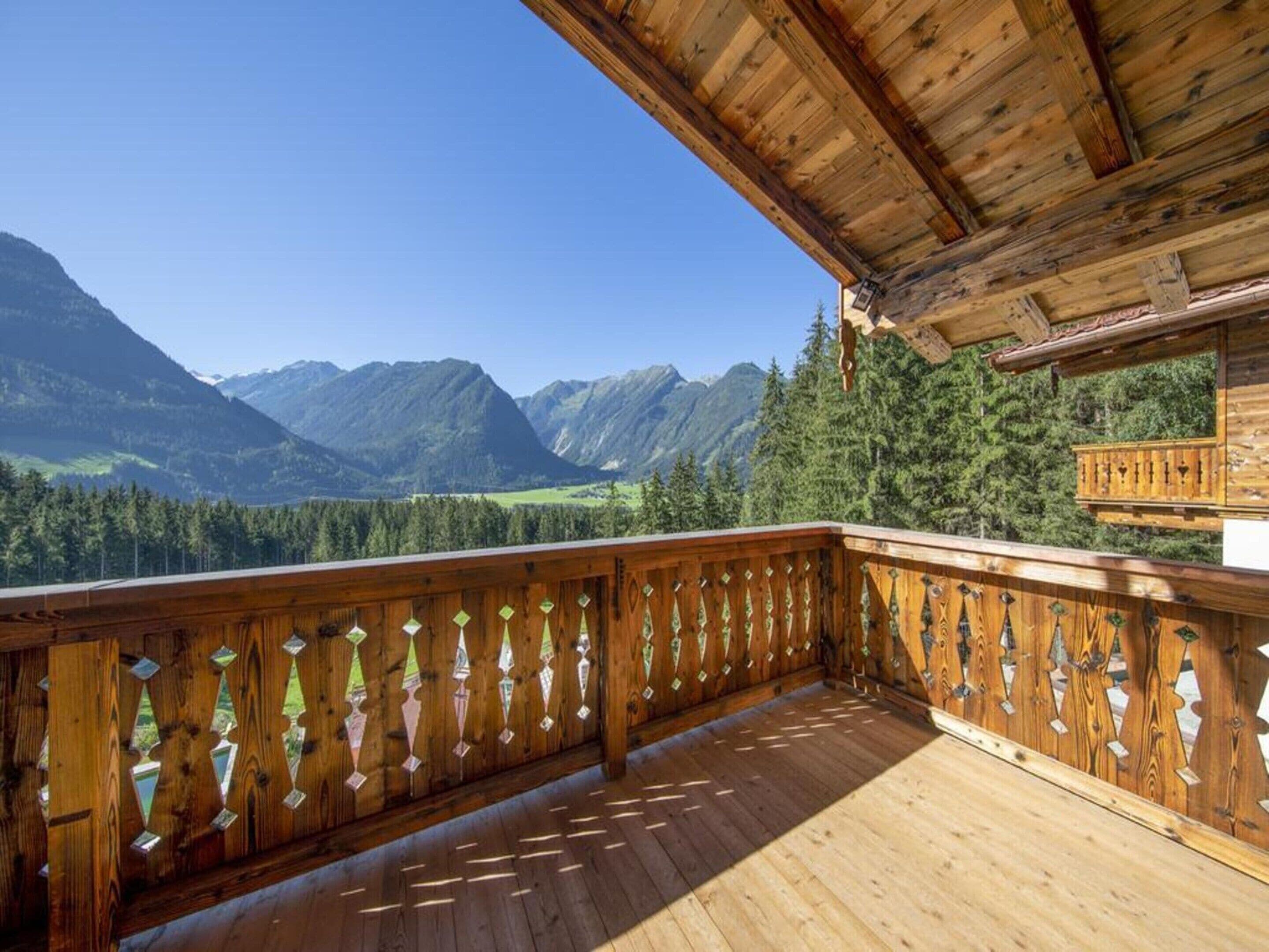 A wooden deck with a view of mountains and forest.