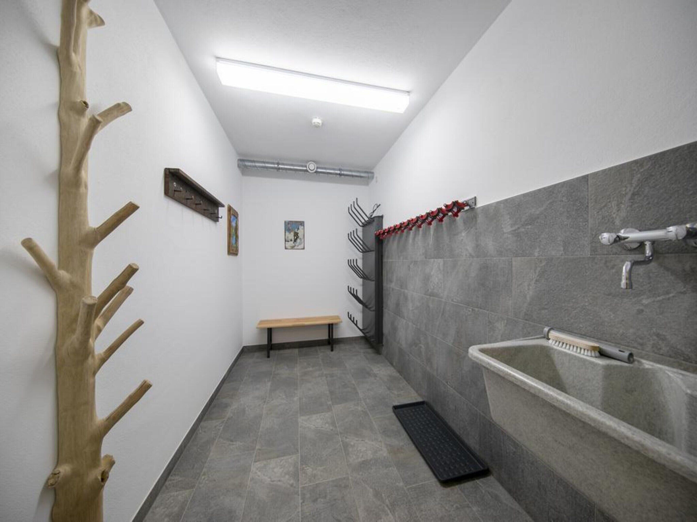 A narrow bathroom with a bench, a sink, and a towel rack.