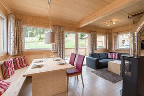 A wooden cabin interior with a dining area, sofa, and fireplace. - Attractive Chalet With hot tub (Sankt Georgen am Kreischberg)