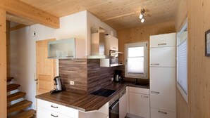 A compact kitchen with wooden cabinets, a built-in oven, and a window. - Attractive Chalet With hot tub (Sankt Georgen am Kreischberg)