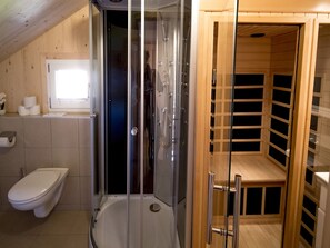 Un bagno moderno con doccia in vetro, un water e una sauna in legno.