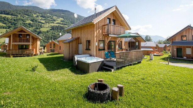 A wooden cabin with a hot tub, deck, and a mountain backdrop. - Attractive Chalet With hot tub (Sankt Georgen am Kreischberg)