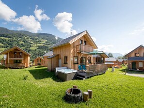 A wooden cabin with a hot tub, deck, and a mountain backdrop. - Attractive Chalet With hot tub (Sankt Georgen am Kreischberg)