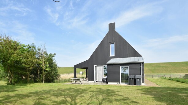 A modern farmhouse with a large open porch, a small attached garage, and a well-maintained lawn. - Seaside Villa With Garden (Tzummarum)