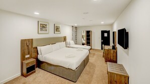 Un dormitorio con una cama grande, mesitas de noche, un armario y un televisor de pantalla plana.