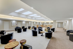 Un vaste espace de détente doté de nombreux sièges, notamment des canapés et des fauteuils, disposés autour de tables.