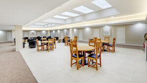 Un comedor amplio con varias mesas y sillas, un techo alto con tragaluces y un diseño limpio y moderno.