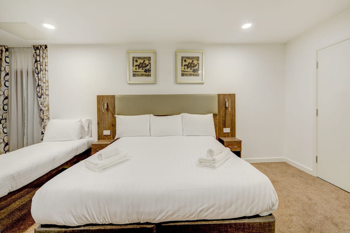 Une chambre d’hôtel avec un grand lit, deux tables de chevet, une tête de lit et deux tableaux encadrés accrochés au mur.