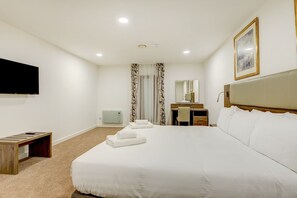 A hotel room with a large bed, a desk, a chair, a television, and a bathroom with a mirror and curtains. - OYO Plymouth Central Hotel (Plymouth)