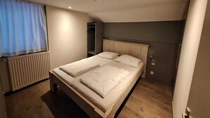 A small, well-lit bedroom with a single bed, a radiator, a wardrobe, and a window with curtains. - Holiday Home in Stramproy Near Nature Reserve (Stramproy)