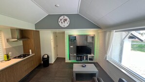 A compact living space with a kitchenette, a TV, and a seating area. - Holiday Home in Stramproy Near Nature Reserve (Stramproy)
