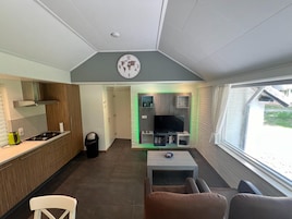 Un espacio habitable compacto con kitchenette, televisor y zona de estar.