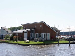 A modern building with a flat roof, large windows, and a covered outdoor seating area with a lawn.