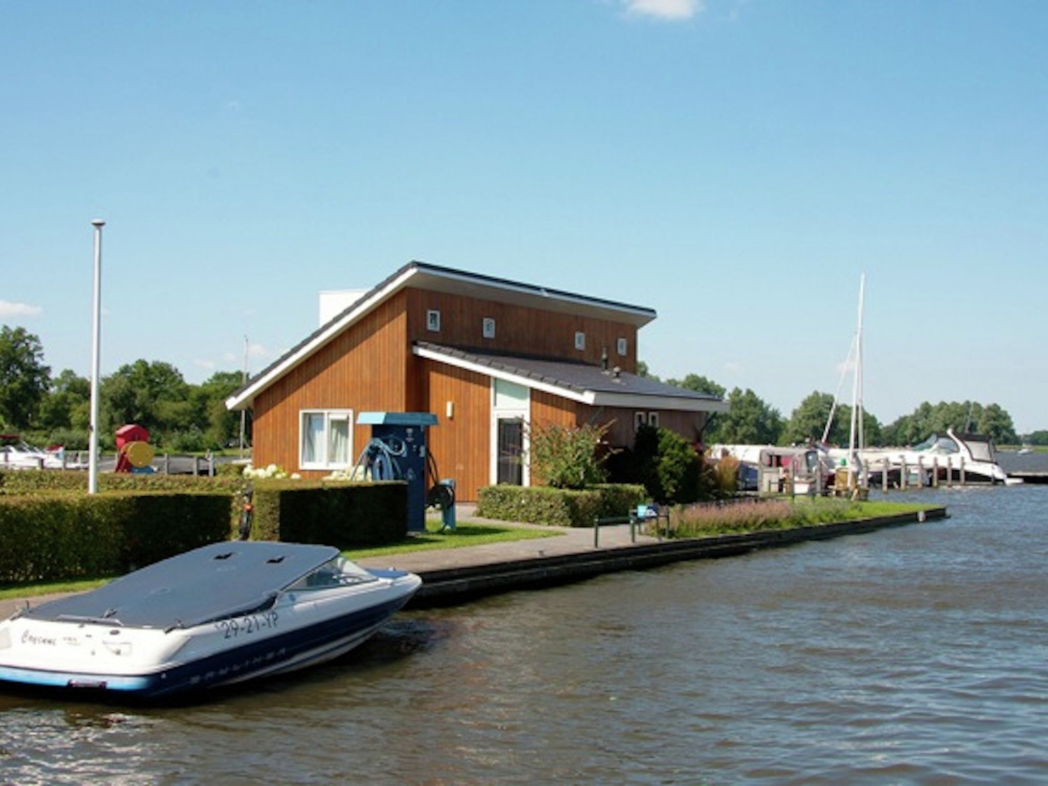 A houseboat docked at a canal with a small dock and a grassy area in front.