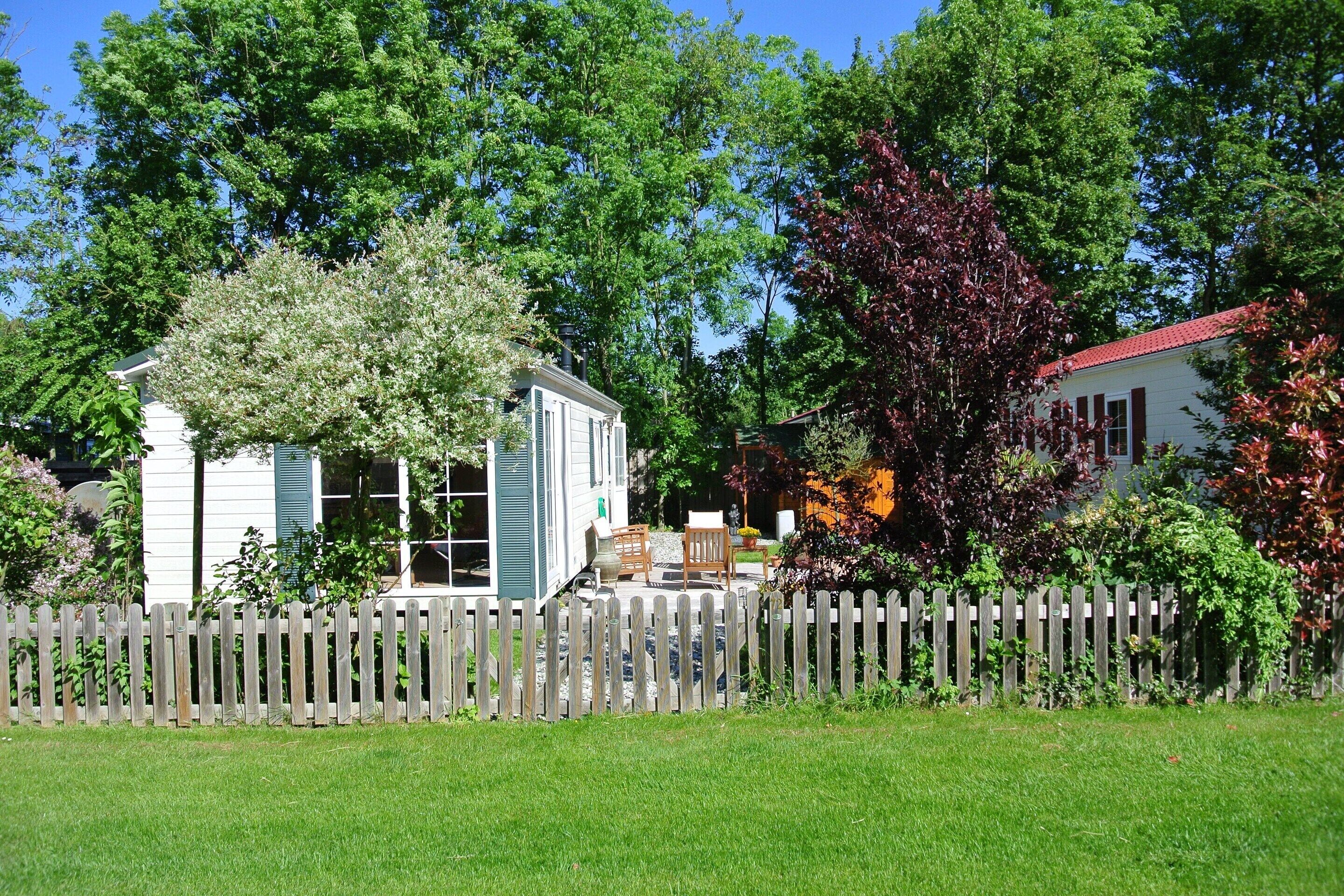A house with a wooden fence, a porch, and a garden.