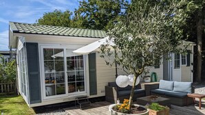 Un espace patio extérieur accueillant, doté d’un coin salon intégré, d’une plante en pot et d’une petite table.