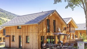A wooden cabin with a balcony, outdoor seating, and a view of the surrounding landscape. - Chalet With Indoor hot tub (Sankt Georgen am Kreischberg)