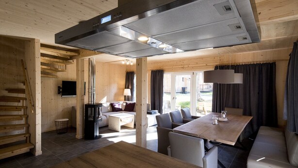 A modern interior with a wooden staircase, a dining area with a table and chairs, a sofa, and a television. - Chalet With Indoor hot tub (Sankt Georgen am Kreischberg)