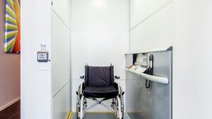 Un ascenseur accessible aux personnes en fauteuil roulant, équipé d’une rampe d’appui et d’un panneau de commande.